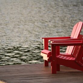 red wooden lounge chair on brown boardwalk near body of water during daytime