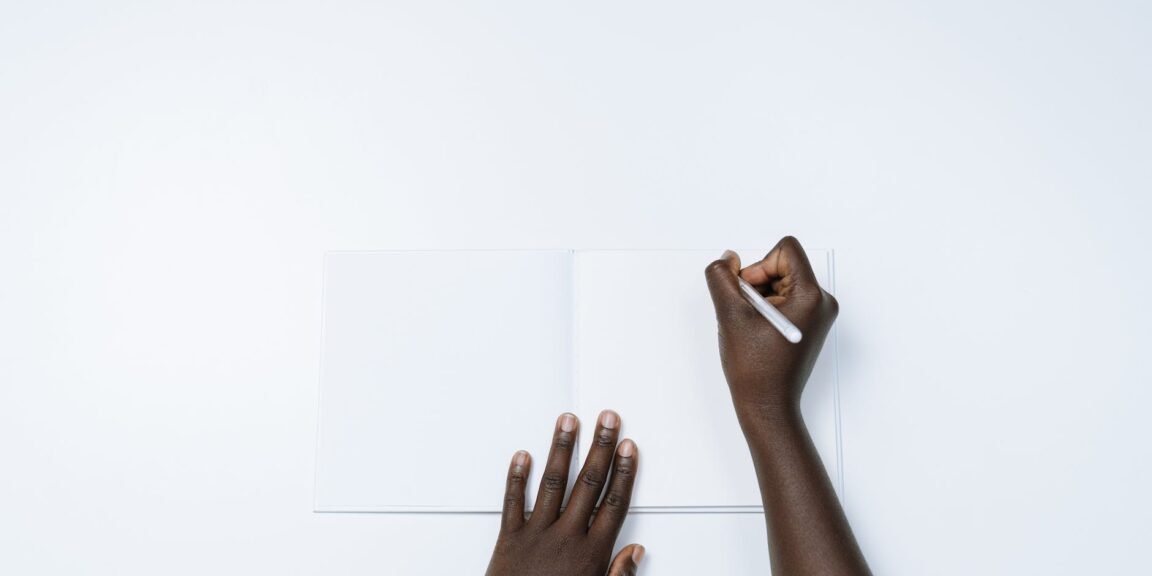 person writing on a white notebook