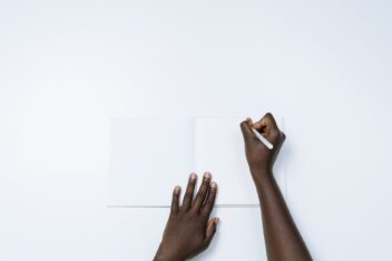 person writing on a white notebook