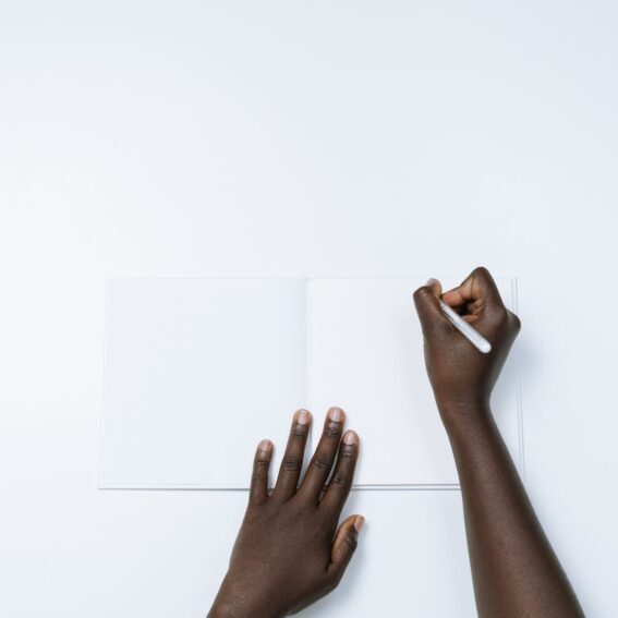 person writing on a white notebook