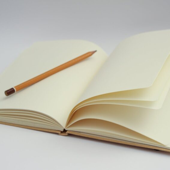 white notebook and yellow pencil